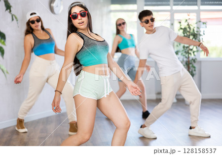 Group of dancers training modern dance moves in studio Group of dancers training modern dance moves in studio 128158537