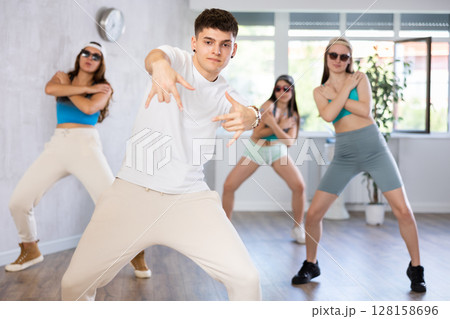 Young b-boy dancing with group of friends in dance studio Young b-boy dancing with group of friends in dance studio 128158696