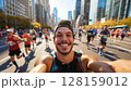 Young man marathon runner taking a selfie while running a marathon, capturing the vibrant atmosphere with a crowd of other runners and the big city skyline in the background, showcasing the excitement 128159012