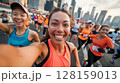 Runner in a marathon, snapping a selfie with a big smile, surrounded by fellow participants and the impressive cityscape in the background, highlighting the energetic and communal spirit of the race 128159013