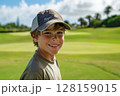Happy caucasian boy at golfing training lesson, smiling at the camera on a sunny golf course, surrounded by lush green fairways and practicing his swing with enthusiasm, enjoying the sport and 128159015