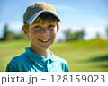 Caucasian boy at a golf training session, happily looking at the camera on a vibrant golf course, engaging in his lesson with eagerness, highlighting the fun and educational aspects of the sport for 128159023