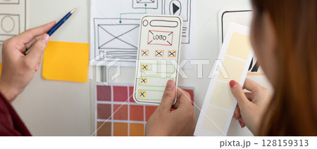 UX and UI Design. Hands holding design mockups and color palettes for mobile app. UX and UI Design. Hands holding design mockups and color palettes for mobile app. 128159313