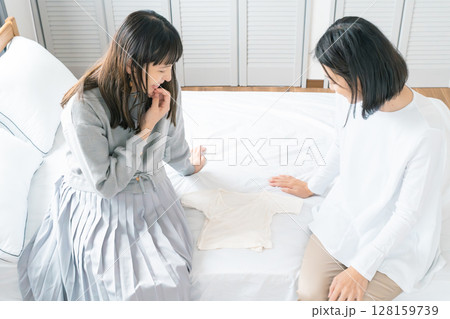 寝室で赤ちゃんの服を準備する母と娘 寝室で赤ちゃんの服を準備する母と娘 128159739