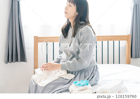 寝室で赤ちゃんの服を準備する妊婦 128159760