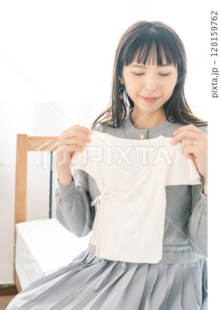 寝室で赤ちゃんの服を準備する妊婦 寝室で赤ちゃんの服を準備する妊婦 128159762