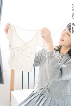 寝室で赤ちゃんの服を準備する妊婦 128159764