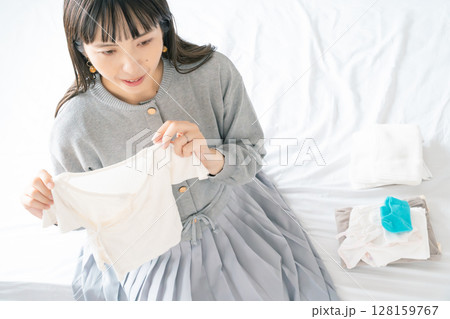 寝室で赤ちゃんの服を準備する妊婦 寝室で赤ちゃんの服を準備する妊婦 128159767