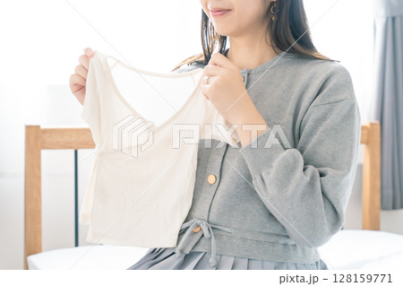 寝室で赤ちゃんの服を準備する妊婦 寝室で赤ちゃんの服を準備する妊婦 128159771