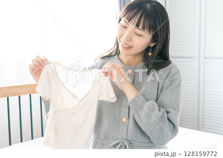 寝室で赤ちゃんの服を準備する妊婦 寝室で赤ちゃんの服を準備する妊婦 128159772