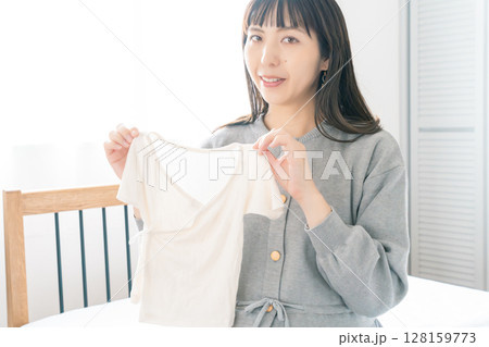 寝室で赤ちゃんの服を準備する妊婦 128159773