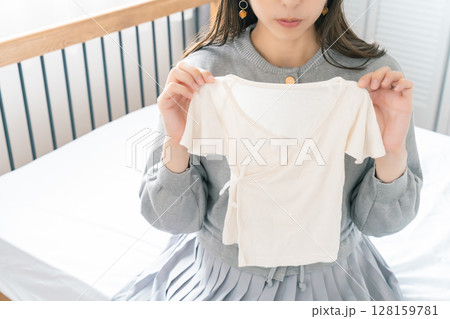 寝室で赤ちゃんの服を準備する妊婦 128159781
