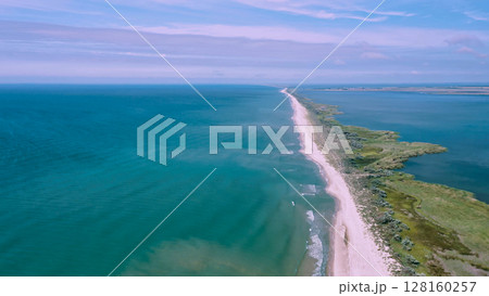 Aerial view of waves on a gritty ocean beach. Oncoming waves crashing against the sandy tropical shore over and over again. Aerial drone top view of sandy and wavy beach. Aerial view of waves on a gritty ocean beach. Oncoming waves crashing against the sandy tropical shore over and over again. Aerial drone top view of sandy and wavy beach. 128160257