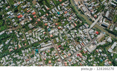 Top view of the roofs of houses of a small town with a river, bridge, cars, boats. Drone view of a small town on a summer day. Top view of the roofs of houses of a small town with a river, bridge, cars, boats. Drone view of a small town on a summer day. 128160270