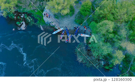 Aerial view of the winning rowers disembarking from boat races on the river. Rowers after the race gathering to award the winners of the competition. Racing boats are moored to the river bank. 128160300
