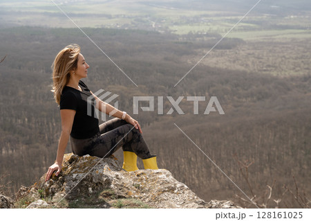 Woman Relaxation Forest: Blonde woman sits on rock, enjoys nature, forest view, daytime for relaxation. Woman Relaxation Forest: Blonde woman sits on rock, enjoys nature, forest view, daytime for relaxation. 128161025