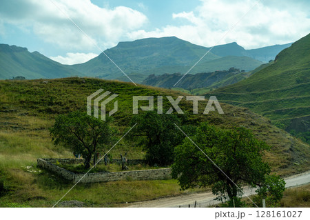 A mountain range with a small house in the middle of the field 128161027