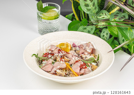 A fresh gourmet salad with sliced roast beef, mushrooms, sun-dried tomatoes, cheese, and greens, served with a refreshing lime and mint drink in a bright, natural setting A fresh gourmet salad with sliced roast beef, mushrooms, sun-dried tomatoes, cheese, and greens, served with a refreshing lime and mint drink in a bright, natural setting 128161643