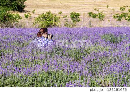Woman taking photo in blooming lavender field under summer sunlight. Concept of lavender as inspiration, natural beauty, hobby, creative relaxation 128161676