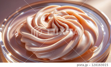 A swirl of cream is in a glass bowl. The cream is light pink and has a smooth texture. The bowl is clear and the cream is visible through the sides A swirl of cream is in a glass bowl. The cream is light pink and has a smooth texture. The bowl is clear and the cream is visible through the sides 128163015