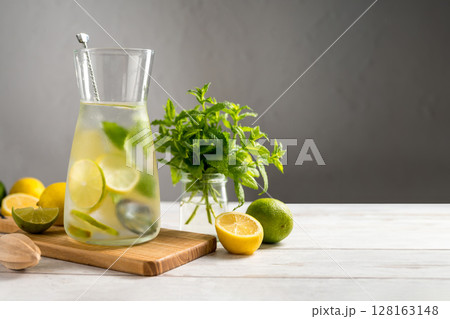 A glass jug with lemonade with lemons, limes and fresh mint, summer drink. Copy space A glass jug with lemonade with lemons, limes and fresh mint, summer drink. Copy space 128163148