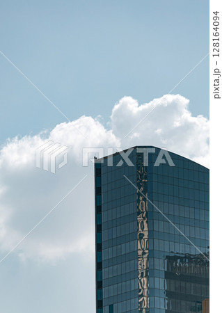 Tall glass building with sky and cloud background 128164094
