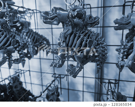 Objects keychains in form of dog skeleton models of toys printed on 3D printer from molten plastic hanging on chain. Concept 3D Printing. Modern 3D Printing additive technology. Blue color 128165034
