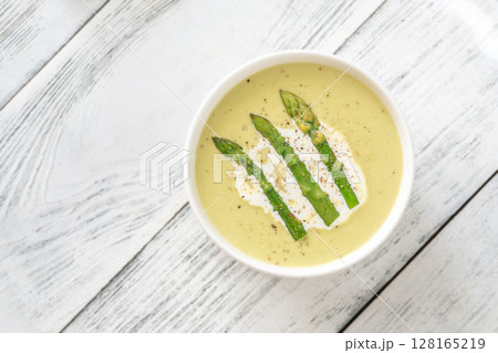 Creamy asparagus soup in white bowl with swirl and toasted ciabatta 128165219