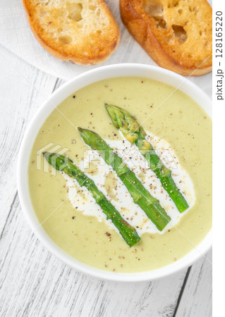 Creamy asparagus soup in white bowl with swirl and toasted ciabatta Creamy asparagus soup in white bowl with swirl and toasted ciabatta 128165220