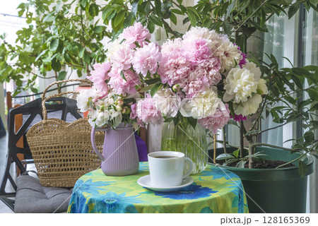 Cup of coffee or tea, bouquet of pink and white peony flowers in vase on a table 128165369