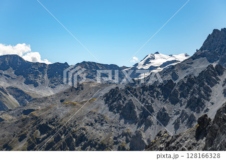 The towering Ortles Mountain stands grand under blue skies, its snowy caps and rugged terrain evincing the serene beauty of the Italian Alps. The towering Ortles Mountain stands grand under blue skies, its snowy caps and rugged terrain evincing the serene beauty of the Italian Alps. 128166328