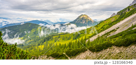 Clouds gently blanket the Low Tauern mountains in Austria, revealing lush green valleys and towering peaks. The tranquil atmosphere invites exploration and adventure in nature's beauty. Clouds gently blanket the Low Tauern mountains in Austria, revealing lush green valleys and towering peaks. The tranquil atmosphere invites exploration and adventure in nature's beauty. 128166340
