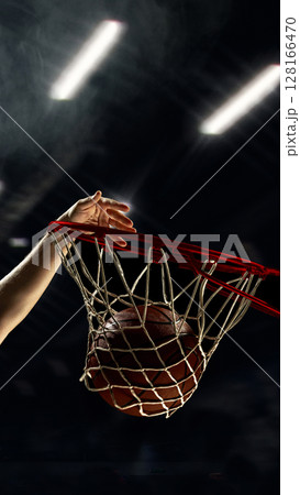 Basketball dunk with player hand pushing ball through hoop 128166470