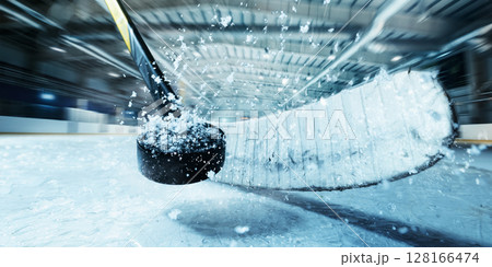 Close-up of hockey stick hitting puck on ice during fast action in indoor 3D rink Close-up of hockey stick hitting puck on ice during fast action in indoor 3D rink 128166474