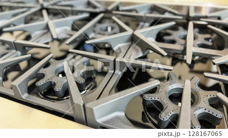 a close-up view of multiple industrial gas stove burners with cast iron grates a close-up view of multiple industrial gas stove burners with cast iron grates 128167065