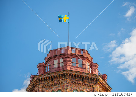 Bredablick Tower top stands tall against a clear blue sky in Skansen, with the Swedish flag fluttering at its peak. Stockholm, Sweden Bredablick Tower top stands tall against a clear blue sky in Skansen, with the Swedish flag fluttering at its peak. Stockholm, Sweden 128167417