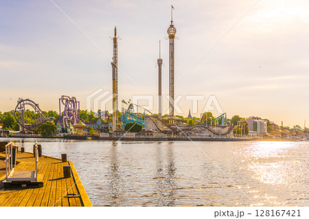 The sun rises on Grona Lund, Stockholms waterfront amusement park, casting a warm glow over the thrill rides and serene waters. The sun rises on Grona Lund, Stockholms waterfront amusement park, casting a warm glow over the thrill rides and serene waters. 128167421