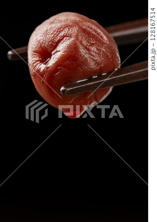 箸で持ち上げられた梅干しのクローズアップ 128167514