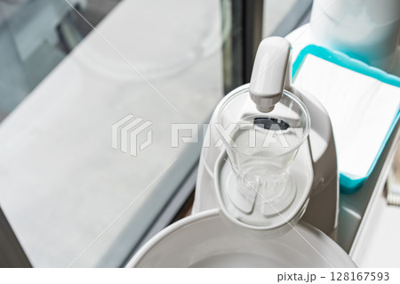 A plastic glass on a cup holder of the modern ceramic mouth cleaning sink in the dentist office near a window, 128167593