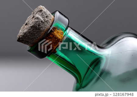 Close-up of a green glass bottle with a cork stopper showcasing unique texture and shape 128167948