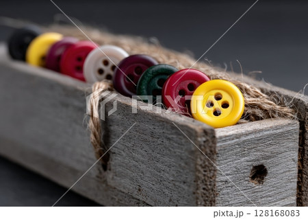 Colorful buttons arranged in a wooden box for sewing and crafting activities in natural lighting 128168083