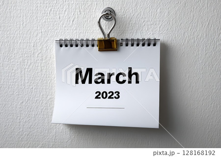 Spiral bound calendar page showing March 2023 hanging on a wall clip 128168192