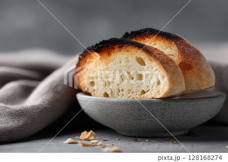 Freshly baked bread served on a rustic plate with a soft linen cloth nearby 128168274