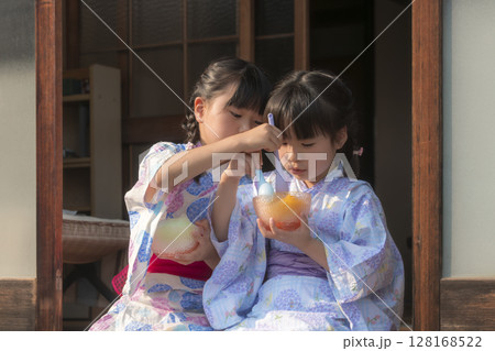 縁側でかき氷を食べる浴衣姿の姉妹 128168522
