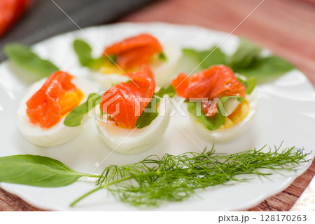 Decorated eggs with red fish and herbs on the table 128170263