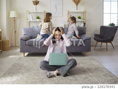 Mother, woman sitting on floor of living room, stressed or overwhelmed with work from home Mother, woman sitting on floor of living room, stressed or overwhelmed with work from home 128170341