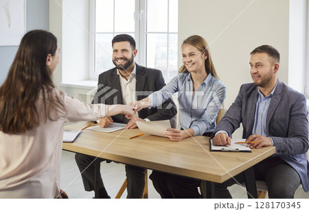 Business people in formal wear accomplishing meeting shaking hands, satisfied after negotiations 128170345