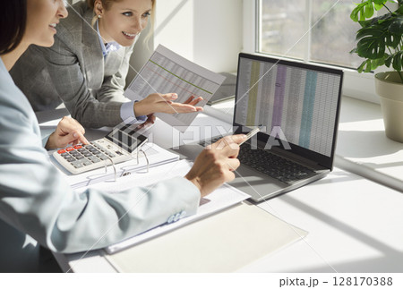 Concentrated businesswomen, female traders looking at laptop screen with stock market data Concentrated businesswomen, female traders looking at laptop screen with stock market data 128170388