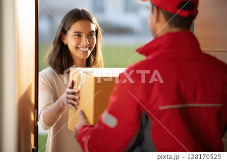 Smiling woman receiving package from delivery man at home Smiling woman receiving package from delivery man at home 128170525