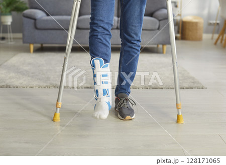Cropped image of unrecognizable man has broken leg, walking on crutches, wearing fracture fixator Cropped image of unrecognizable man has broken leg, walking on crutches, wearing fracture fixator 128171065